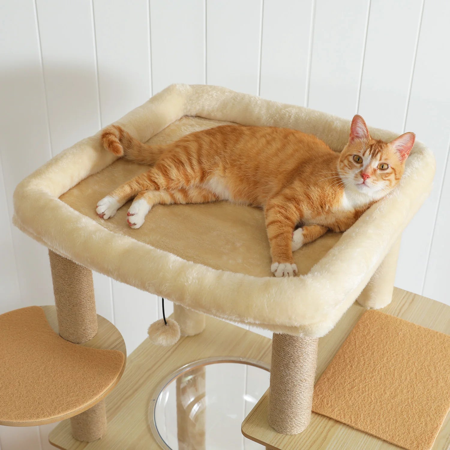 Orange cat lounging on a beige cat tree with wooden accents against a white wall.